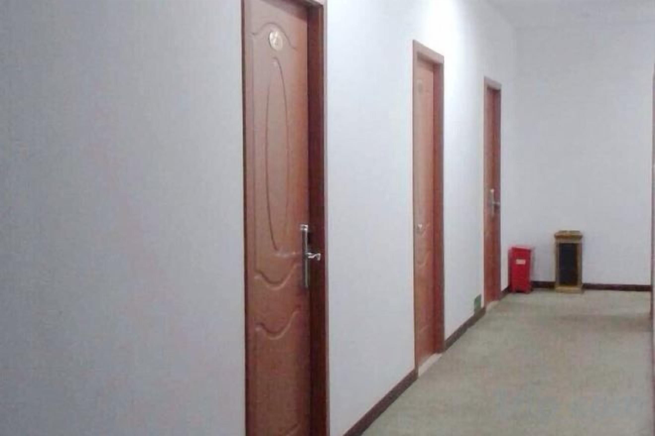 A hallway with closed wooden doors and a red trash bin.