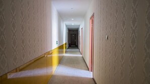 Passadís llarg i estret amb parets amb dibuixos i terra amb moqueta, que condueix a una porta al final.