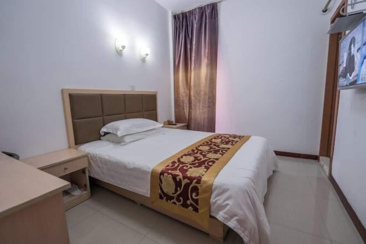 A bedroom with a bed, bedside table, and a wall-mounted TV.