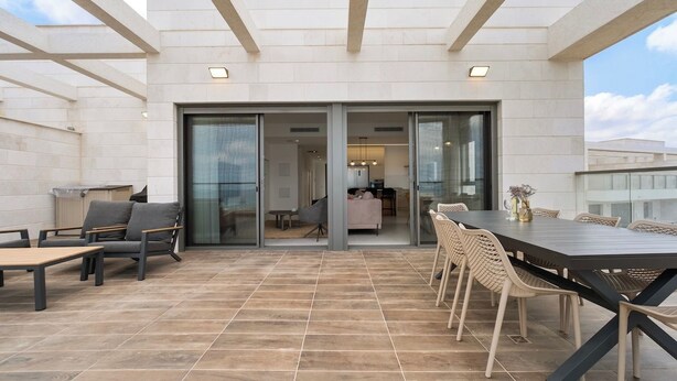 An outdoor patio area with a dining table and chairs, a sofa, and a view into the building. - Mamad Achziv Seaside Stylish Stay (Nahariya)