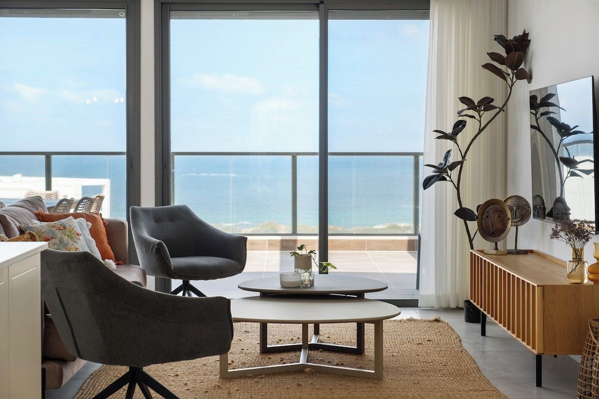A modern living room with a large window, a round coffee table, and a sofa.