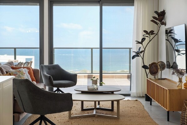 A modern living room with a large window, a round coffee table, and a sofa.