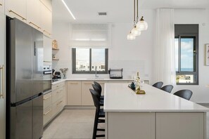 A modern kitchen with a large island, stainless steel appliances, and a view to the outside.