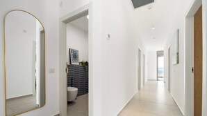 A hallway with a mirror, a toilet, and a framed picture on the wall. - Mamad Achziv Seaside Stylish Stay (Nahariya)