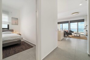 Una camera d'albergo moderna con un letto, una scrivania e vista sul mare.
