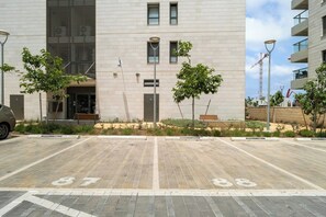 A building with a modern design, featuring a paved entrance area with numbered parking spaces.