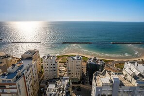 A coastal cityscape with high-rise buildings, a beach, and a clear sky.