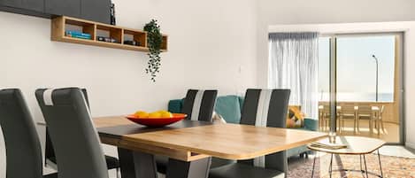 Un comedor moderno con una mesa de madera, sillas negras y un tapiz colorido.