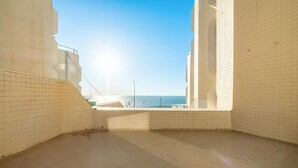 Un balcon spacieux avec vue sur la mer, des murs carrelés et un ciel dégagé.