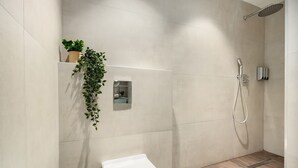 Un baño moderno con ducha, inodoro y una planta en maceta.