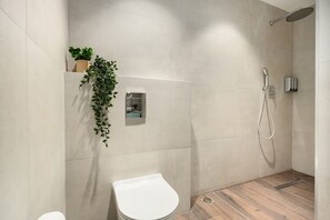 Un bagno moderno con doccia, WC e una pianta in vaso.