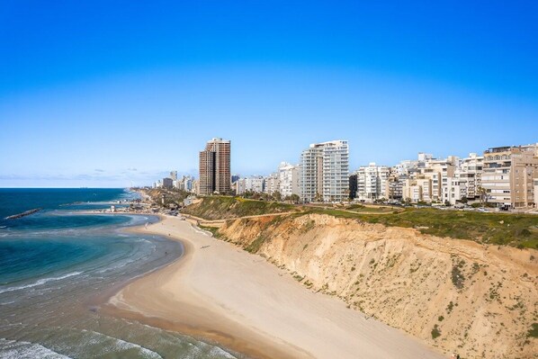 A coastal cityscape with a sandy beach and high-rise buildings.