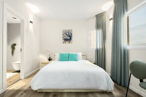 Camera da letto moderna con un letto grande, un comodino, una lampada a parete e una finestra con tende.