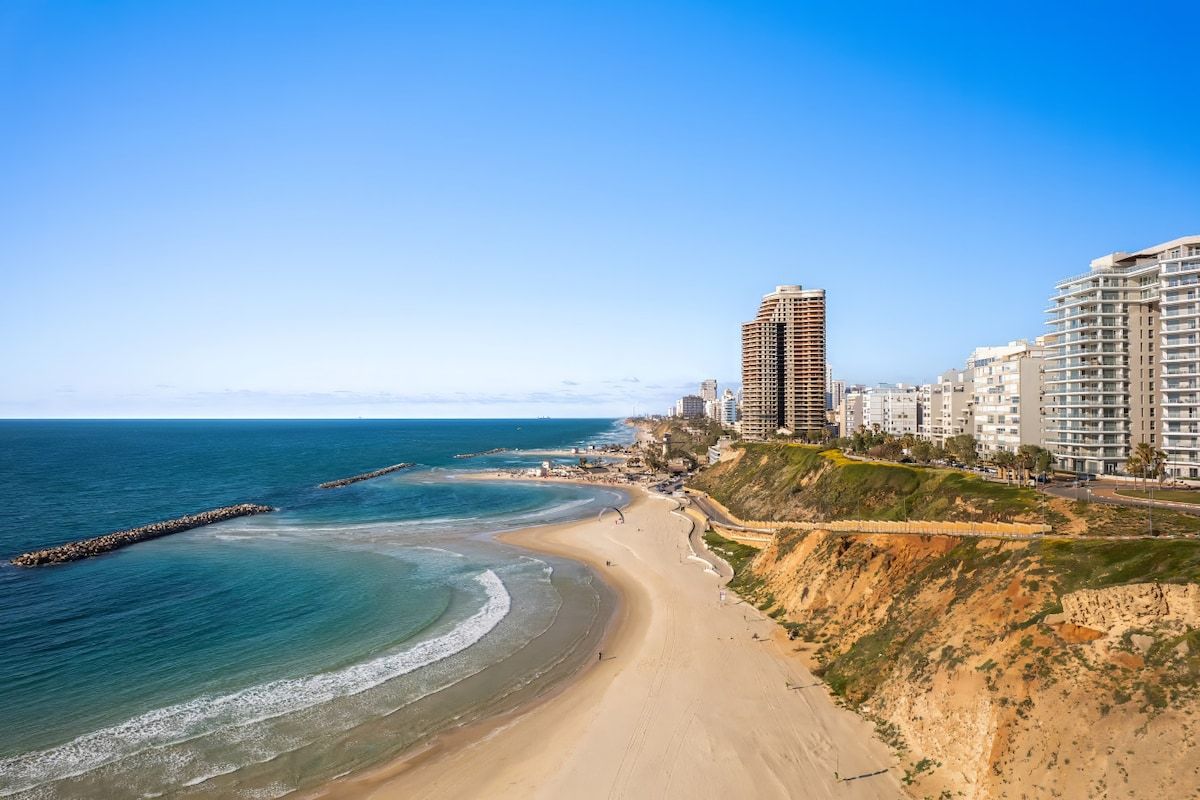 Un paysage urbain côtier avec une plage, des immeubles de grande hauteur et un ciel dégagé.