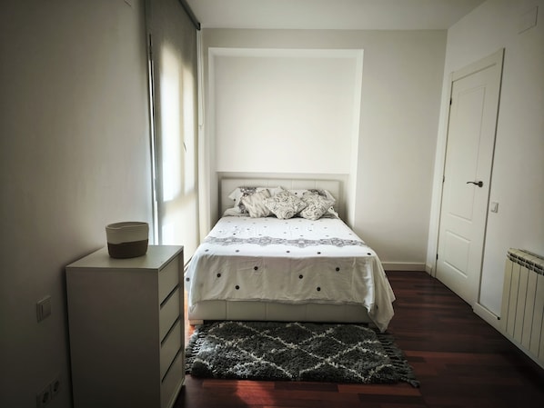 A bedroom with a bed, a dresser, a window, and a door.