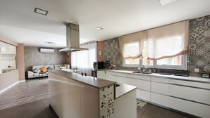 A modern kitchen with a central island, a dining area with a sofa, and a large window with curtains. - Villa with a private pool, 25 minutes from Barcelona (Vallromanes), near the F1 circuit (Vallromanes)