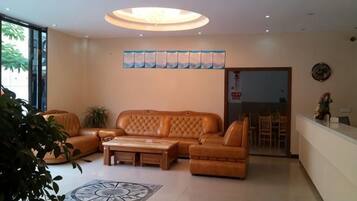 Una sala de estar moderna con sofá, mesa de centro y sillas. Se ve un comedor a través de una puerta de vidrio.