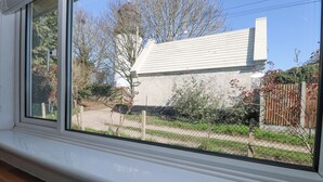 Une cuisine avec une fenêtre donnant sur un quartier résidentiel, où l’on peut voir une maison et une clôture.