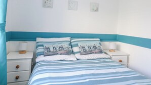 Une chambre à coucher comprenant un lit, deux tables de chevet et trois éléments de décoration murale.