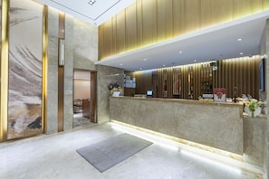 A reception area with a marble floor, a reception desk, and a wall-mounted security camera.