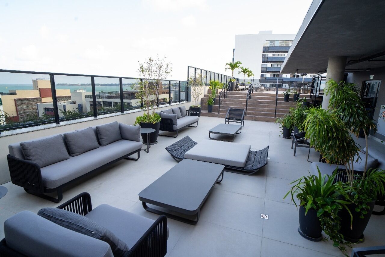 A rooftop terrace with a grey sofa, lounge chairs, and potted plants.
