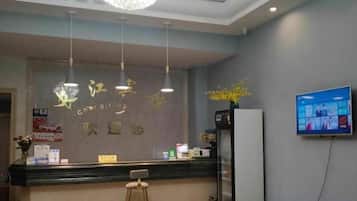 Un espace d’accueil comprenant un comptoir, un téléviseur fixé au mur et un luminaire au plafond.