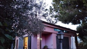 A building with a pink facade, a brick column, and a door with shutters. - Luxury villa in residence in Sicily  (Messina)