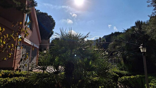 A sunny courtyard with a building, lush greenery, and a street lamp. - Luxury villa in residence in Sicily  (Messina)