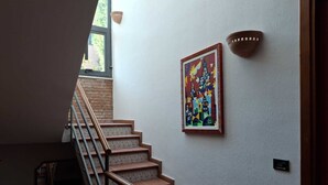 A staircase with patterned tiles, a wall-mounted light fixture, and a framed abstract painting. - Luxury villa in residence in Sicily  (Messina)