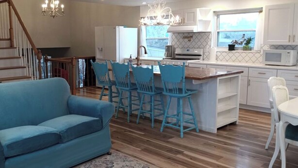 A modern kitchen with a central island, bar stools, and a dining table. - Spacious 6-bedroom house with WiFi, fitness room in peaceful Thornton (Thornton)
