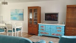A living room with a TV, wooden cabinets, and teal upholstered furniture. - Spacious 6-bedroom house with WiFi, fitness room in peaceful Thornton (Thornton)