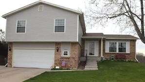 A two-story house with a garage, a front porch, and a small front yard. - Spacious 6-bedroom house with WiFi, fitness room in peaceful Thornton (Thornton)