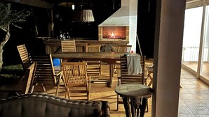 Une terrasse extérieure dotée d’une cheminée en briques, de meubles en bois et d’un sol carrelé.