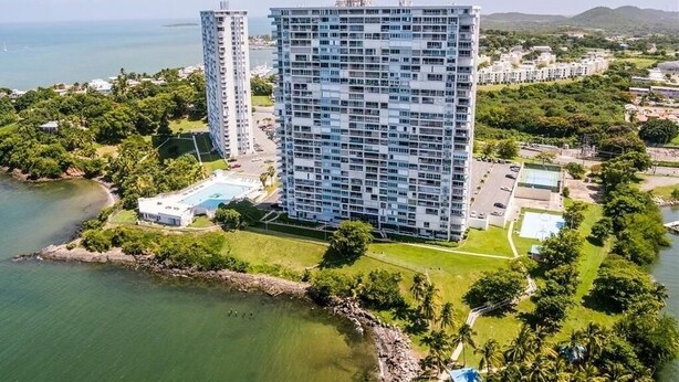 Un hotel moderno de gran altura con varias plantas, piscina y vista al océano.