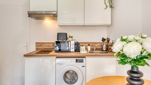 A compact kitchen with a washing machine, microwave, and a wooden countertop.