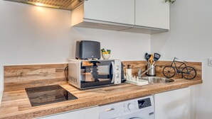 A compact kitchen with a built-in microwave, toaster, and dishwasher, featuring a wooden countertop and a hanging plant.