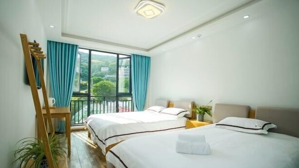 Ein Hotelzimmer mit zwei Betten, einem Balkon, einer Holzleiter und Blick auf Grünflächen.