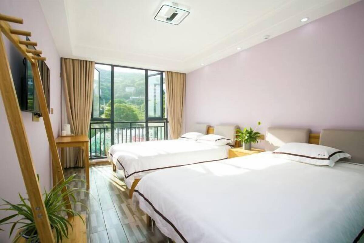 Habitación de hotel con dos camas, televisión, balcón y vista a zonas verdes.