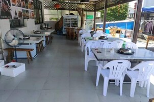 Un restaurante con terraza, mesas, sillas y un ventilador.