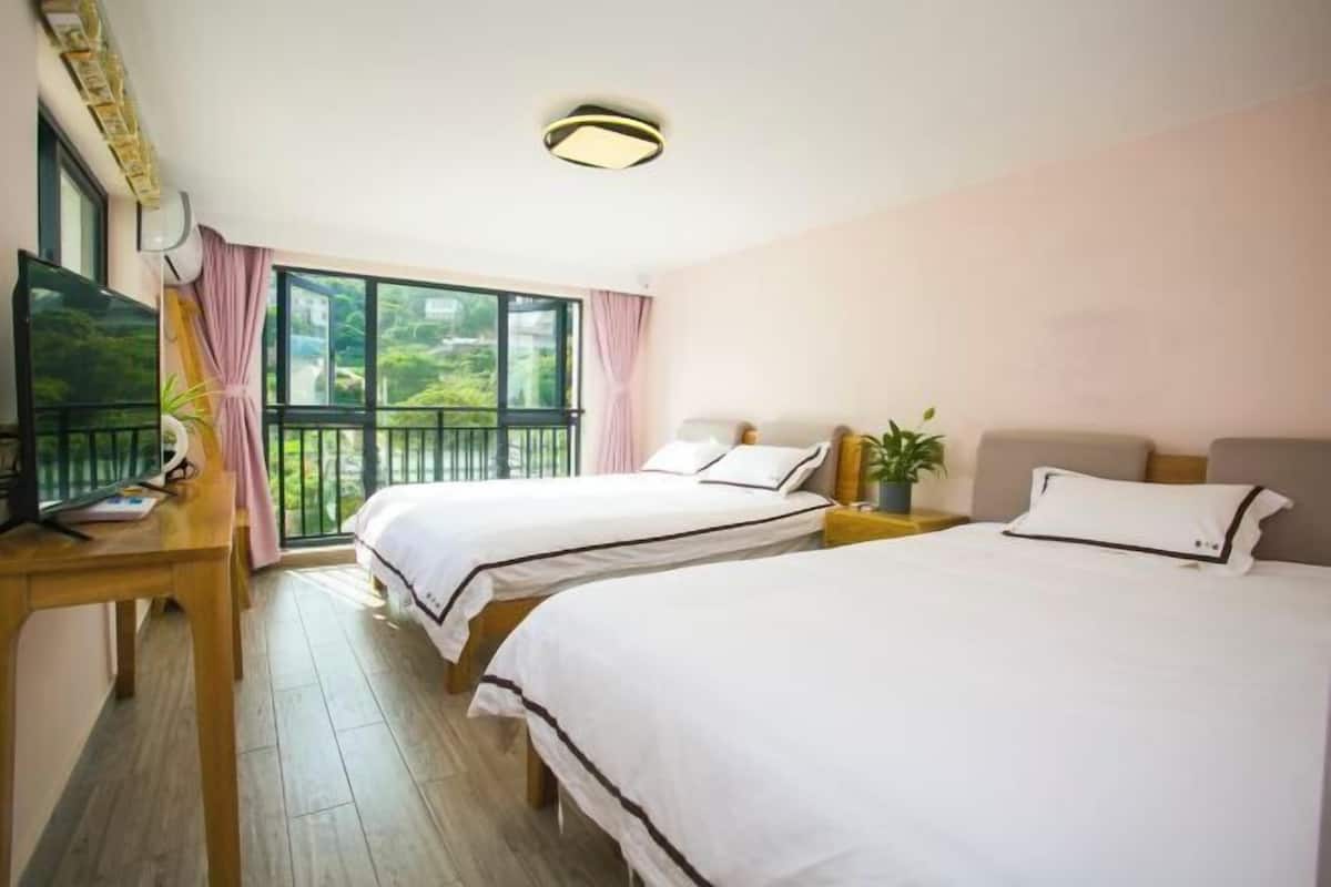 Una habitación de hotel con dos camas, un escritorio, un televisor y un balcón con vistas.