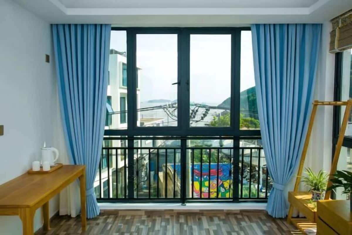 Una habitación con un amplio ventanal, una mesa de madera y vistas a un colorido mural exterior.