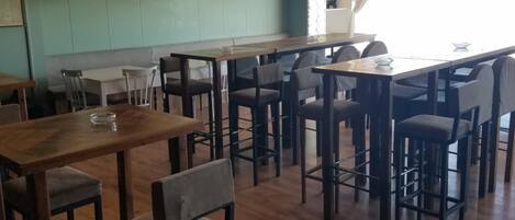 Un ristorante con tavoli e sedie in legno, un muro in mattoni e lampade a sospensione.