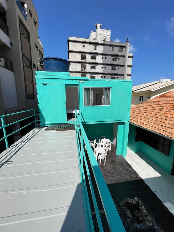 Une terrasse sur le toit, agrémentée d’une structure turquoise, de chaises en plastique blanches et d’une petite piscine.