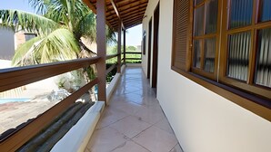 A covered corridor with a tiled floor, wooden railings, and large windows with blinds. - Porto D Aldeia - Cabo Frio RJ - 1 (Sao Pedro da Aldeia)