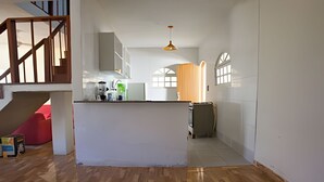 A spacious kitchen with white cabinets, a wooden floor, and a staircase leading to another level. - Porto D Aldeia - Cabo Frio RJ - 1 (Sao Pedro da Aldeia)