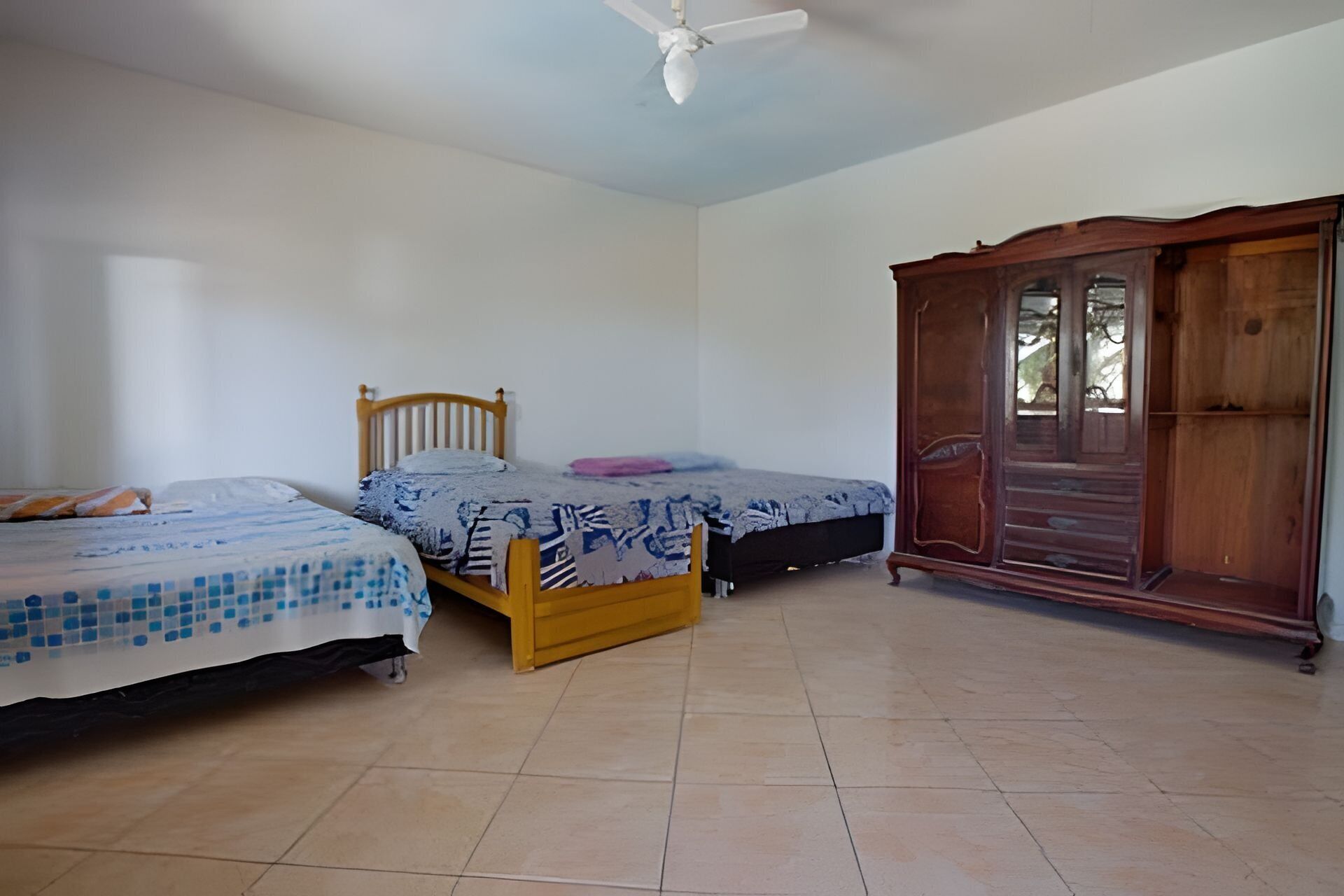 Un dormitorio con dos camas, un armario de madera y un ventilador de techo.