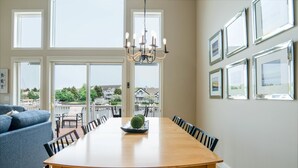 A dining area with a wooden table, black chairs, a chandelier, and framed pictures on the wall.