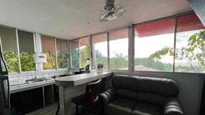 A modern kitchen with a bar area, a dining chair, and a sofa.