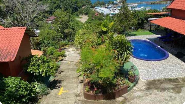 A residential area with a swimming pool, lush greenery, and a view of the ocean.