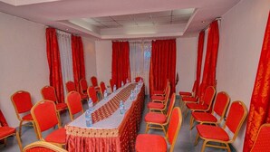 A conference room with a long table, red chairs, and a patterned tablecloth. - Sheron Hotel Kampala (Kampala)